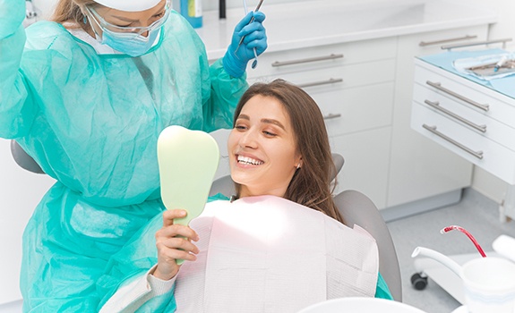 Dental patient admiring her smile in the mirror