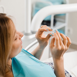 Patient in treatment chair holding clear aligner