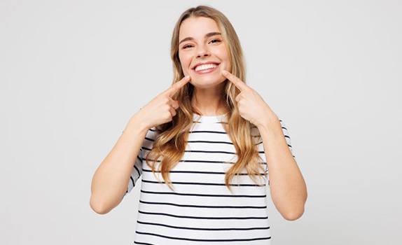 Happy young woman pointing at her teeth