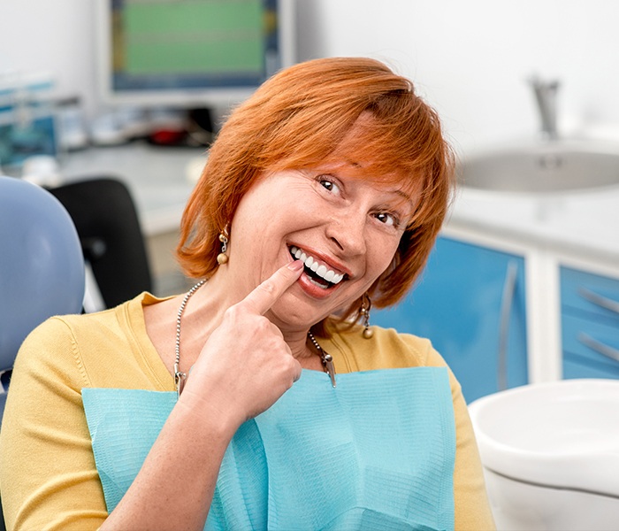Woman pointing to healthy smile during periodontal maintenance visit