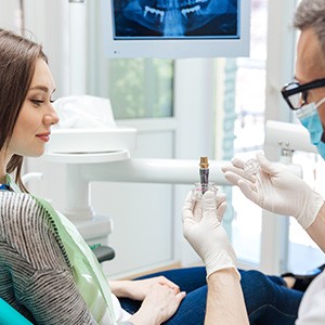 A dentist showing a dental implant to his patient