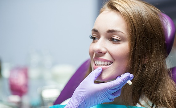 Woman in purple dental chair smiling as dentist inspects results