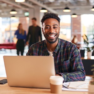 Man smiling while working on laptop in office